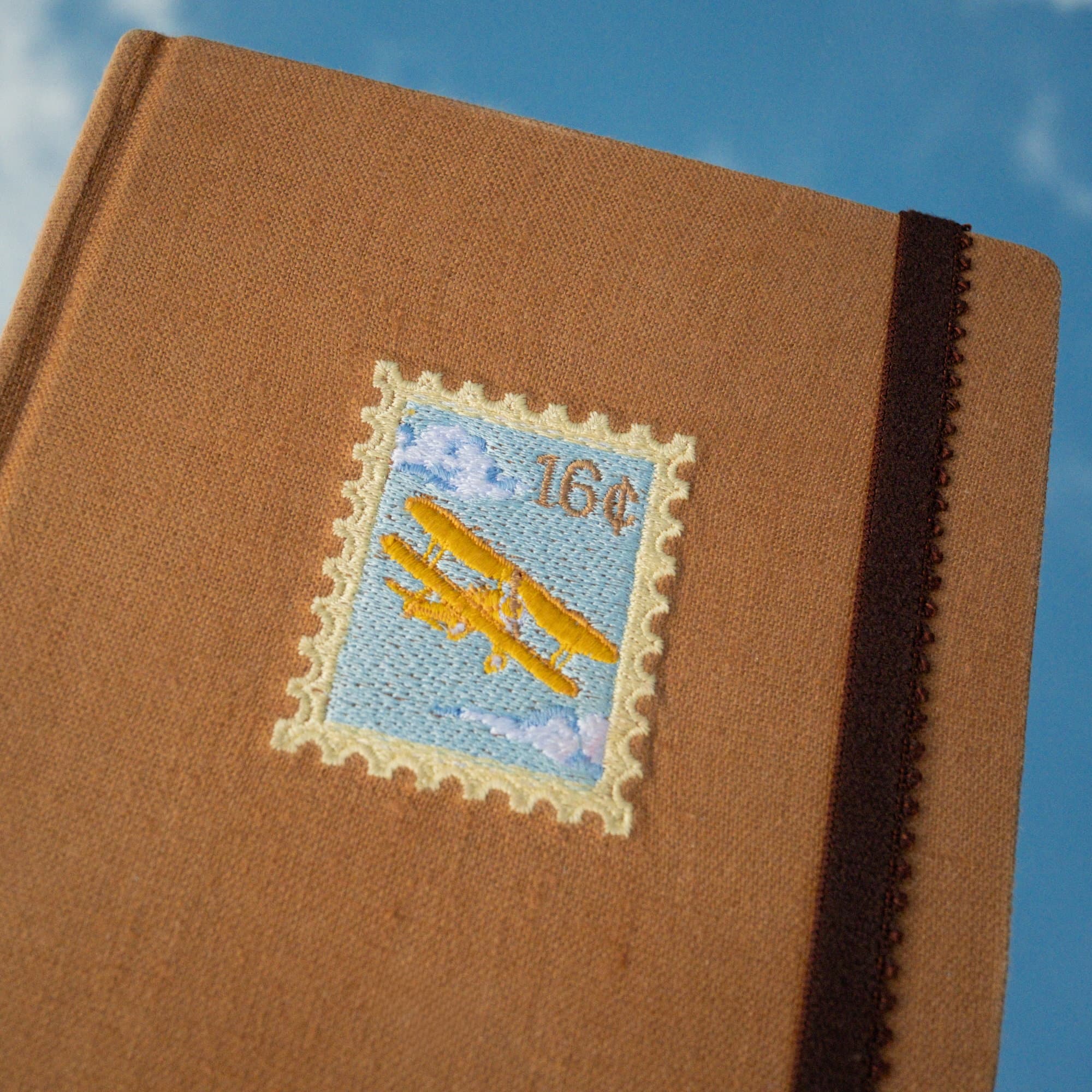 Detalle del bordado de la estampilla con un avión en la portada del journal Correo aéreo.