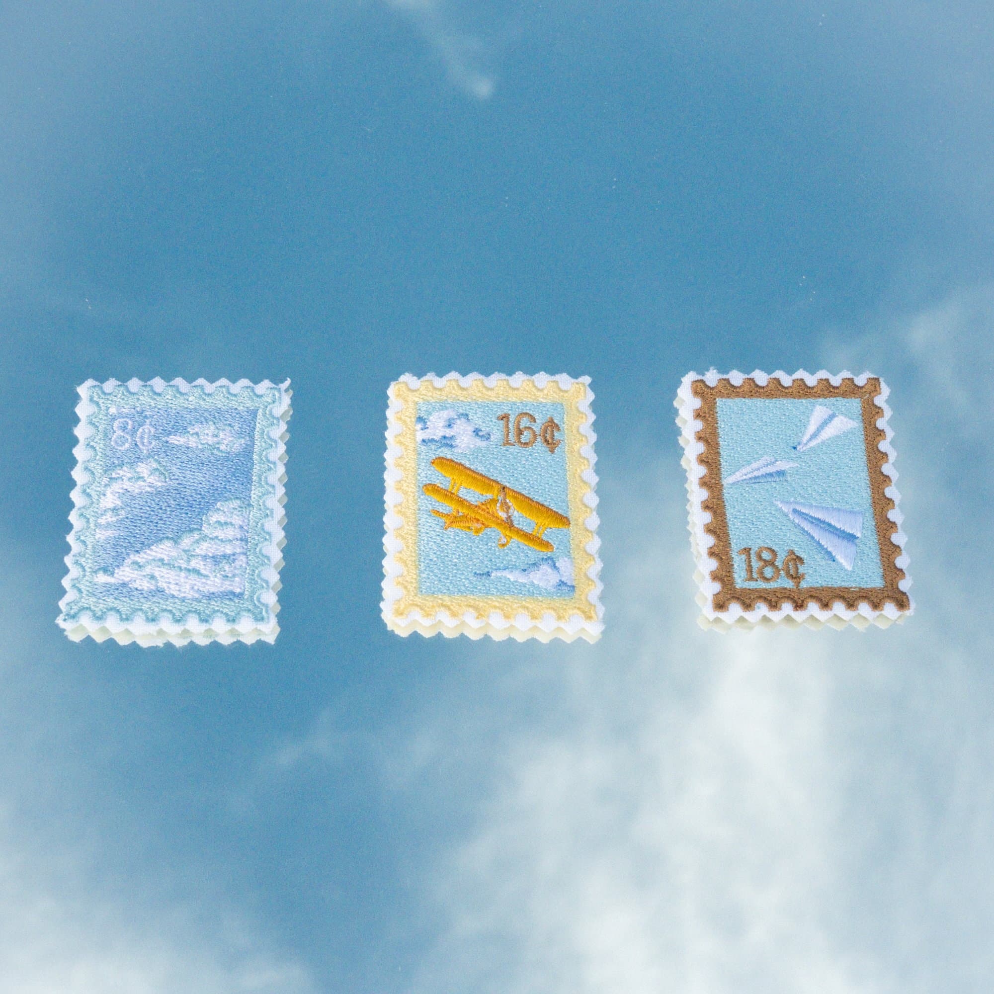 Los tres parches bordados del kit El club del cielo azul, en forma de estampilla.